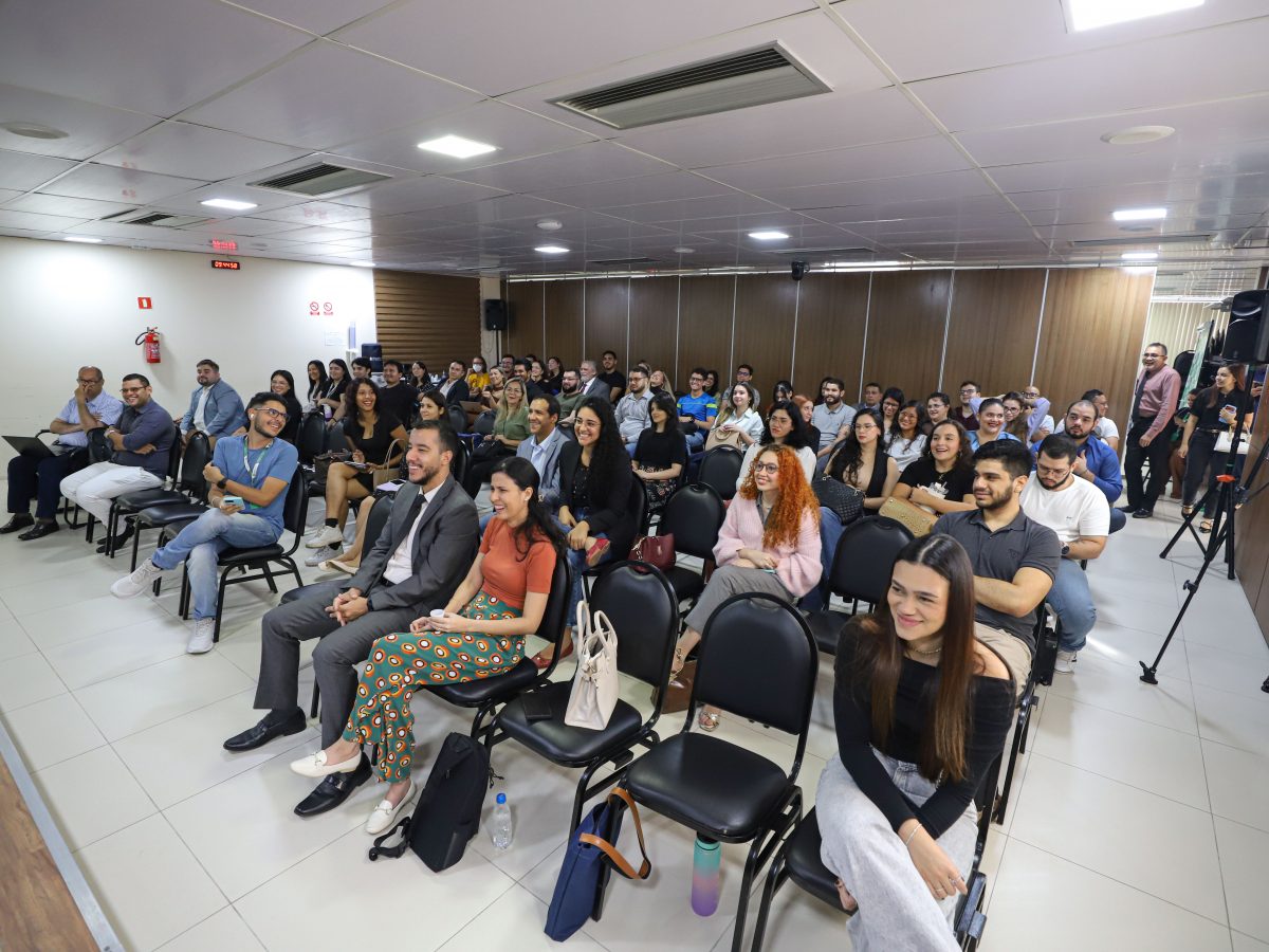 A imagem mostra o auditório da DPE-AM, com as pessoas sentadas assistindo a uma palestra
