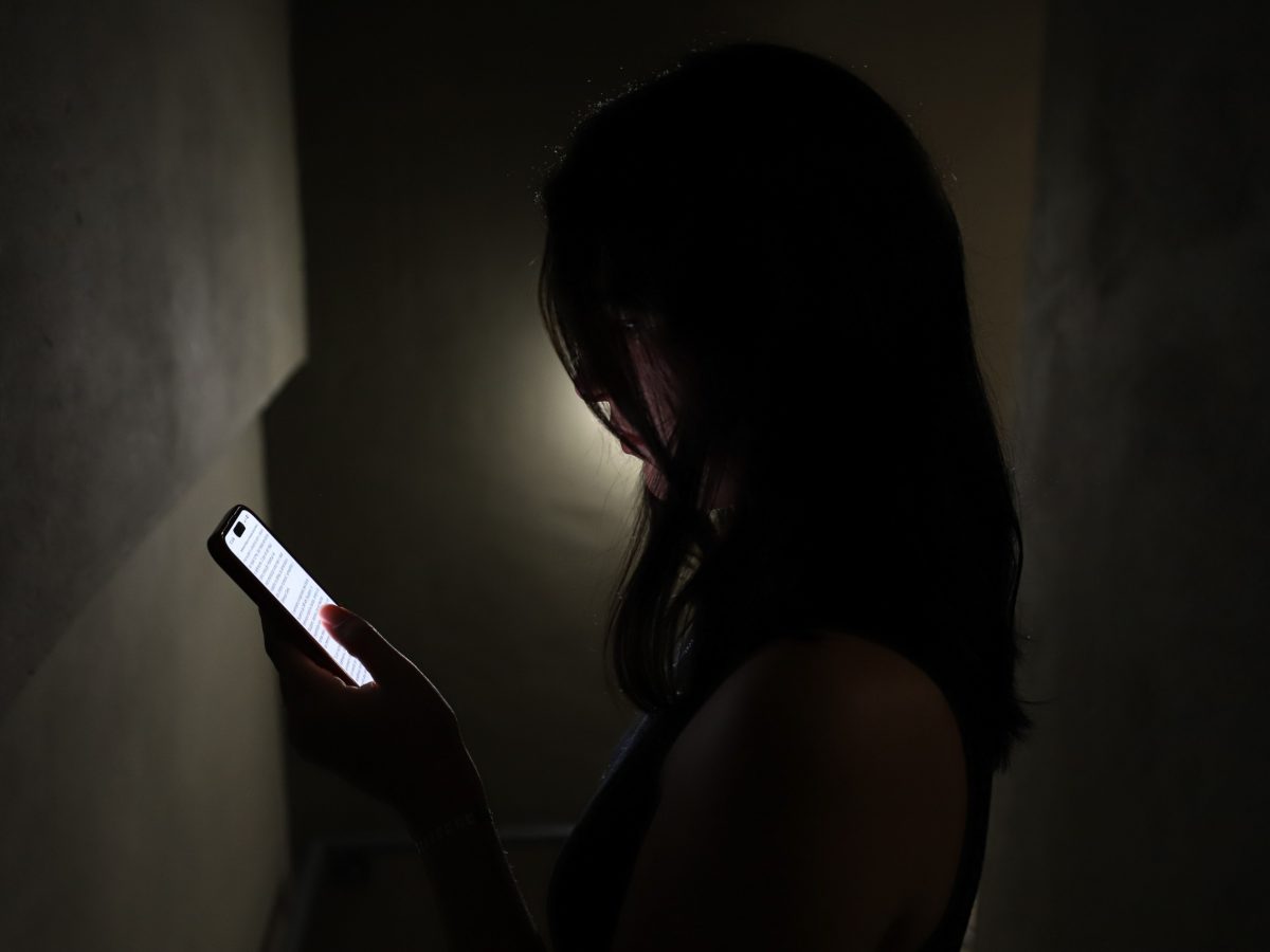 Mulher com o celular na mão, lendo as mensagens