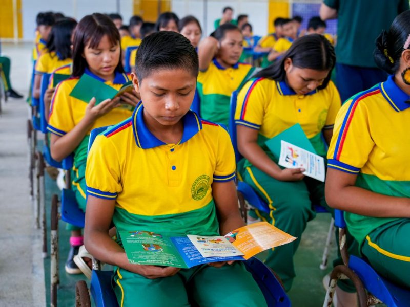 Estudante indígena lê folder dos projetos Defensoria nas Escolas e Caminhos da Inclusão