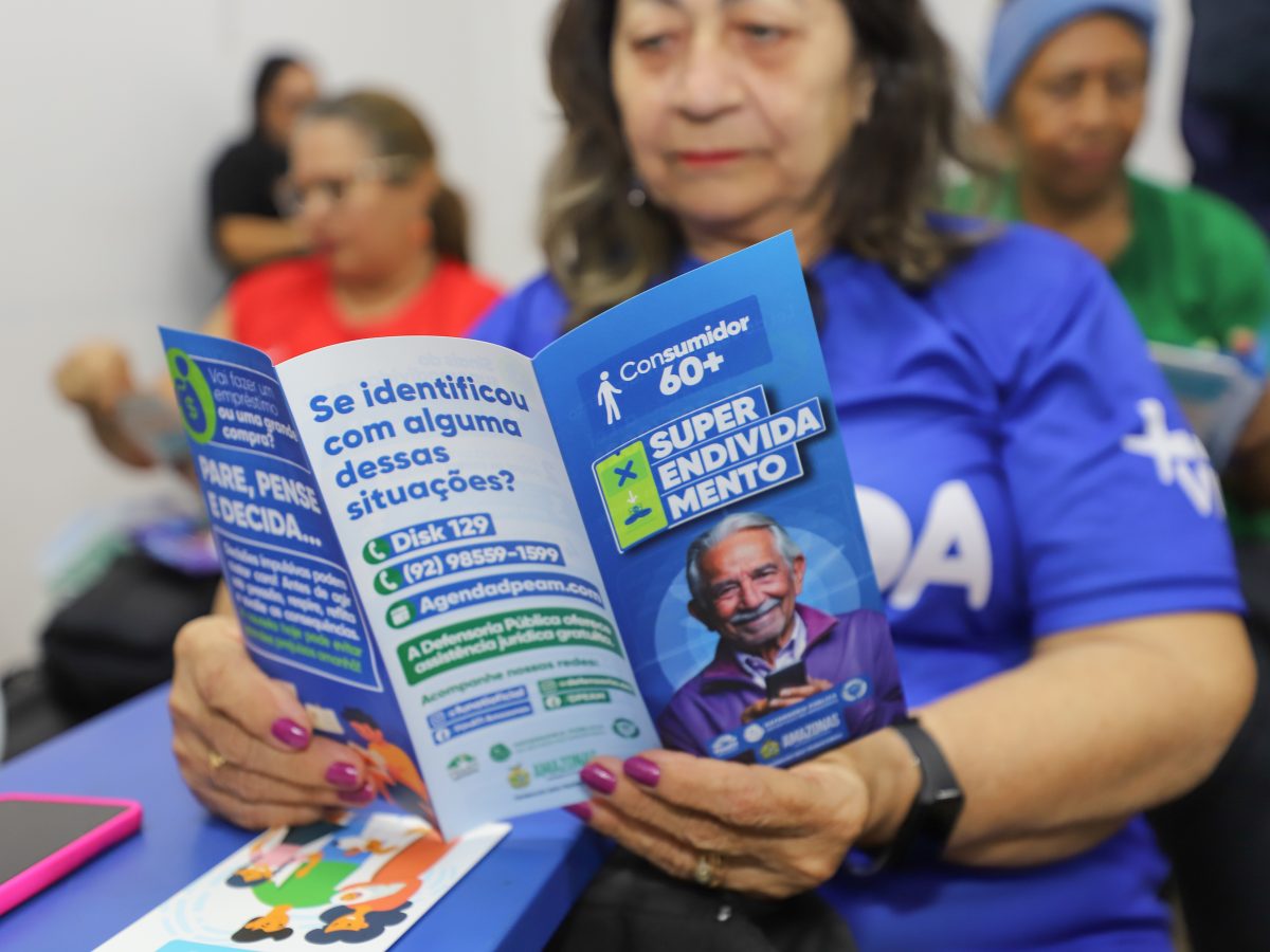 Idosa lê folder com orientações sobre direitos do consumidor