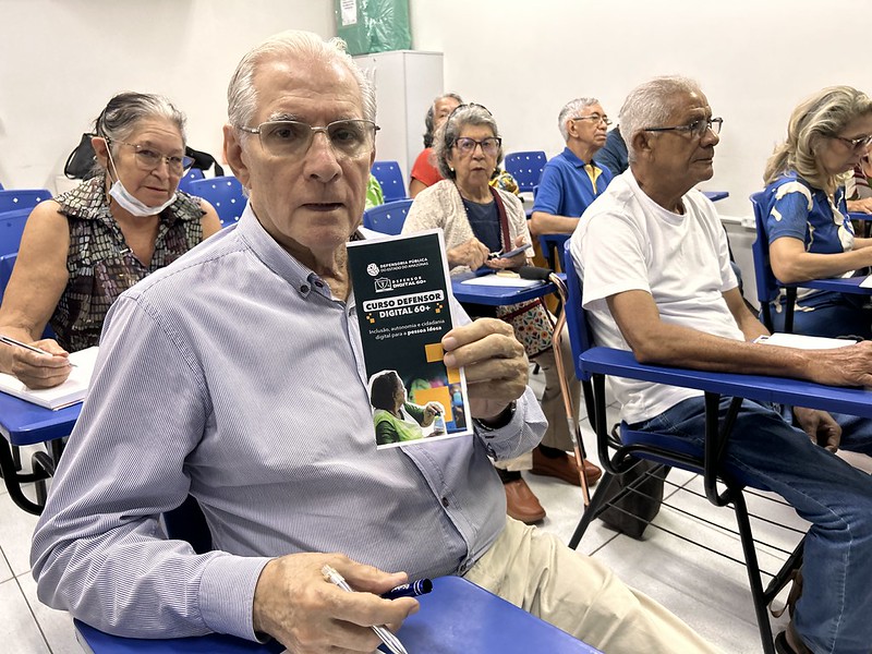 Idoso segura folder do projeto Defensor Digital 60+