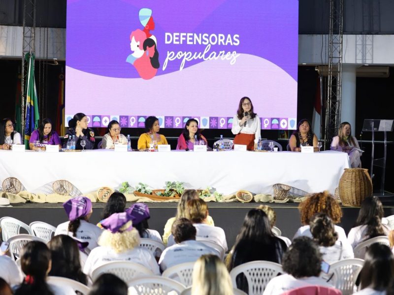 Um projeto de mulheres feito para mulheres, que trabalha a ampliação do acesso à Justiça e da rede de proteção. Esses são os objetivos do Defensoras Populares, lançado, neste sábado (23/05), no Centro Cultural dos Povos da Amazônia, na Avenida Silves, no Distrito Industrial. A iniciativa é uma parceria do Ministério da Justiça e Segurança Pública (MJSP), da Fundação Oswaldo Cruz (Fiocruz) e Fundação de Apoio à Fiocruz (Fiotec) com a Defensoria Pública do Estado do Amazonas (DPE-AM). O lançamento aconteceu apenas com a presença de representantes femininas do Judiciário, Executivo e Legislativo, fortalecendo a missão do projeto de ter mulheres no centro das discussões que envolvem seus direitos. No Amazonas, 120 alunas foram selecionadas para atuarem no projeto, que tem a missão de formar mulheres em situação de vulnerabilidade socioeconômica para identificarem violências de gênero, orientarem outras mulheres sobre como buscar ajuda e aproximarem quem mais precisa dos serviços públicos de justiça. O papel da representatividade A 2ª Subdefensora Pública Geral, Sarah Lobo, esteve presente no evento de lançamento e destacou a importância da iniciativa para fortalecer a atuação feminina e a defesa de direitos individuais e coletivos, especialmente em comunidades mais distantes dos centros urbanos. “A Defensoria Pública ser uma parceira nesse projeto tem um valor muito grande, porque a Defensoria tem justamente a missão constitucional de proteger pessoas em situação de vulnerabilidade. Nosso país é marcado por desigualdades históricas e excludentes e ter um projeto de educação popular que potencializa a voz dessas mulheres é gratificante”, destacou. Para a Secretária Nacional de Acesso à Justiça do Ministério da Justiça e Segurança Pública, Sheila de Carvalho, lançar o projeto no Amazonas é muito representativo, considerando os desafios geográficos e situação de vulnerabilidade da população que vive em boa parte do interior do estado. “A ideia é que elas sejam agentes comunitárias de Justiça e a partir dessa formação elas consigam defender seus direitos e os direitos da comunidade. A parceria com a Defensoria Pública é muito importante, porque, por diversas vezes, é a instituição que a população mais vulnerabilizada busca primeiro”, destacou. É o que também acredita a diretora-presidente da Fiocruz Amazônia, Stefanie Lopes, que destacou a expectativa para o início do curso no Amazonas. “Foi muito lindo ver o impacto que o projeto tem para essas mulheres. Nós percebemos a empolgação delas, desde esse início, e essa parceria fortalece a atuação de cada uma no interior”, disse. Moradora do município de Itacoatiara, a Berenice Castro faz parte de um projeto que acolhe mulheres vítimas de violência doméstica. Empolgada, ela contou como foi ver seu nome na lista de selecionadas do projeto e o que sonha daqui para a frente. “Fiquei muito feliz, porque vou poder ajudar muitas mulheres. Elas podem chegar aonde elas quiserem, é isso que eu penso. Meu objetivo é pegar as ideias que vão surgir aqui e levar para elas, mostrar que elas podem crescer e existe essa possibilidade”, pontuou. Como vai funcionar o curso No Amazonas, o curso de formação acontecerá em Manaus, Itacoatiara e Tefé com foco em abordagens como acesso à justiça para o enfrentamento da violência contra mulher, leis e direitos sobre saúde, família, trabalho, questões raciais e como inserir mulheres nos espaços de decisão, tem a duração de oito meses de encontros presenciais e online. O formato de ensino será híbrido, com aulas presenciais e online, e servirá para a elaboração de um Plano de Articulação Comunitária (PAC Popular), que define as ações que as defensoras populares poderão realizar na comunidade para fortalecer direitos e mobilizar pessoas em prol do acesso à justiça. Texto: Camila Andrade Fotos: Lucas Silva / DPE-AM.